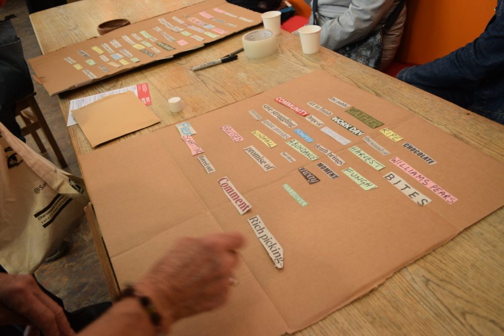 People cutting out words from a newspaper and sticking them on piece of cardboard