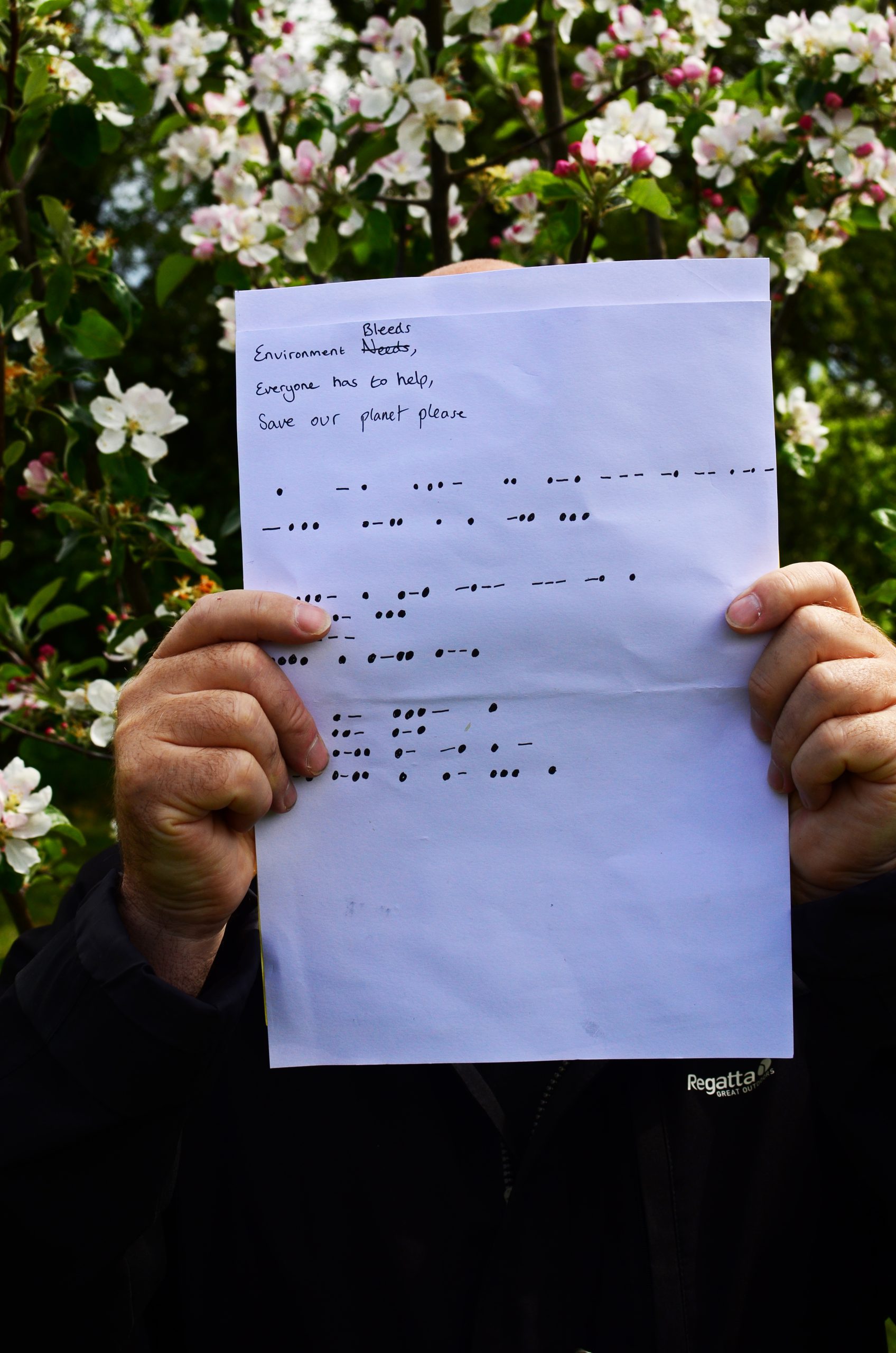 A poem written on a piece of paper, reads: "Environment bleeds (needs crossed out), Everyone has to help), Save our planet please". Followed by Morse Code