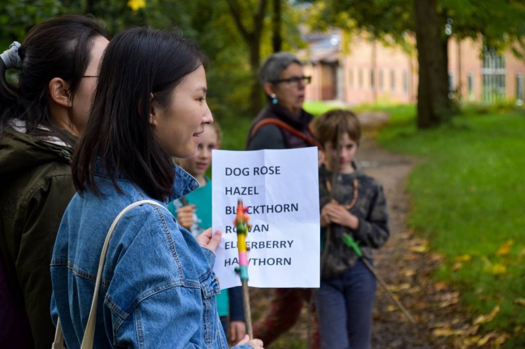 A group of people. One is holding a piece of paper that reads "Dog rose, Hazel" then the rest is obscured.