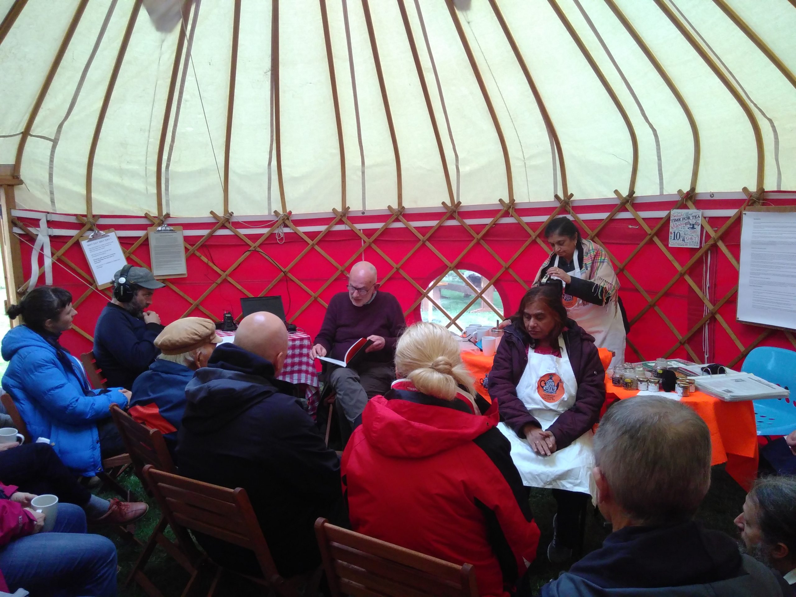 People sitting inside a yurt listening to another person talk