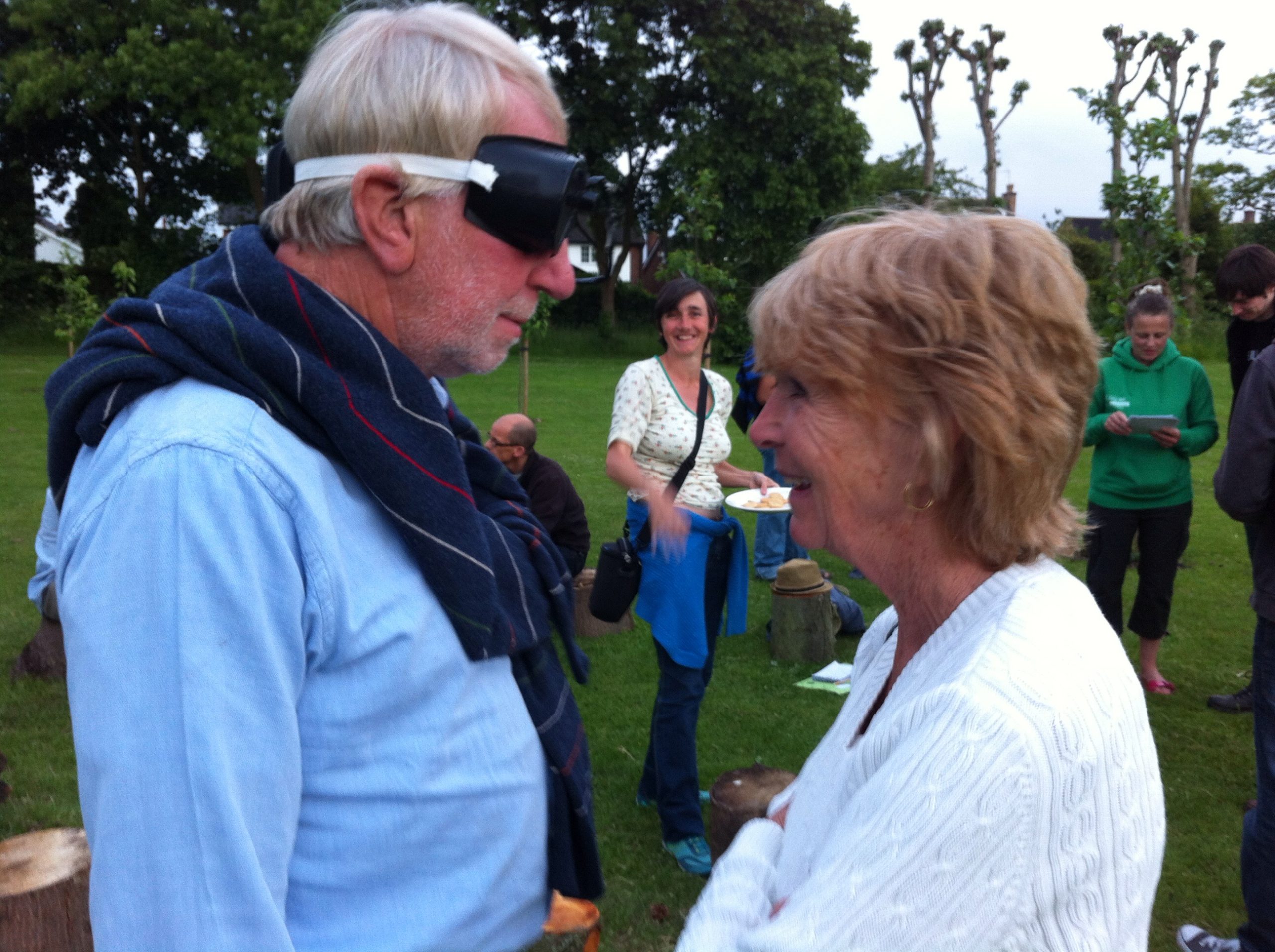 A man and woman standing opposite each other. The man is wearing blacked out goggles.