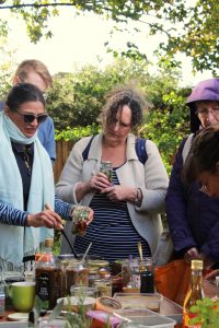 Group of adults in a garden filling jam jars to make pickles and preserves
